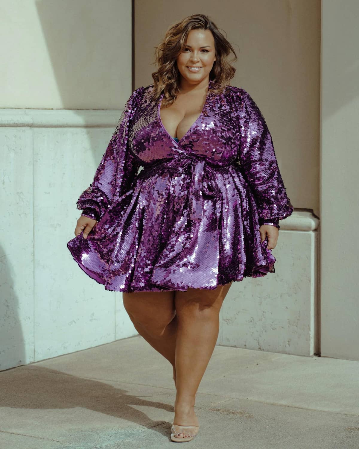 Femme souriante en robe sequinée violette, silhouette grande taille valorisée